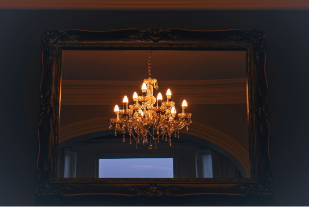 A shot of an electric light powered Neo-classical inspired designer chandelier in a darkened room